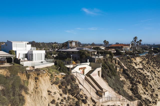 Low aerial view of the cliffs, palm trees and homes in Encinitas.