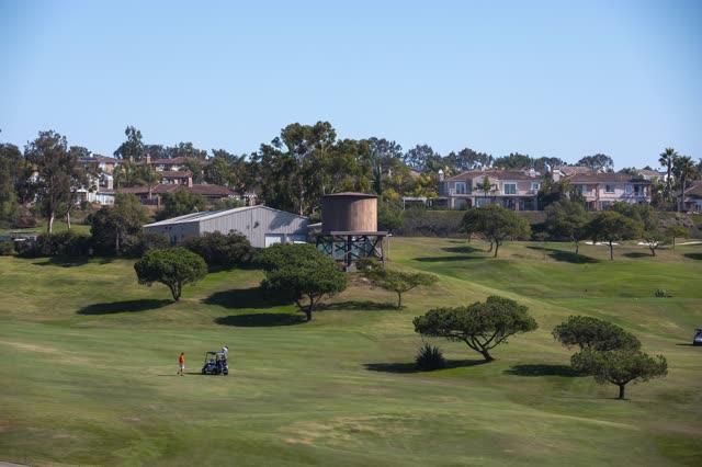 A park, homes and the buildings in Encinitas, with people walking.