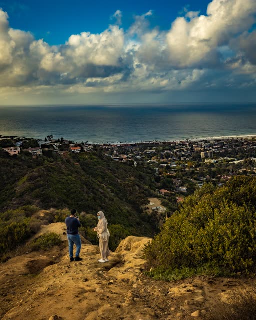 Elevated view of the cliffs, the ocean and homes at Mount Soledad, with a crowd gathered.
