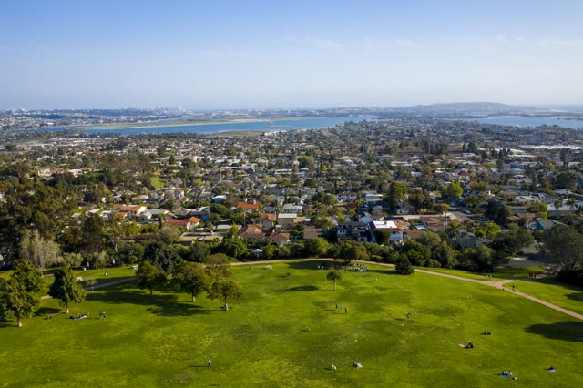 Aerial view of a park, the skyline and the bay in Pacific Beach, with a crowd gathered.
