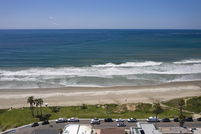 Aerial view of the beach, the surf and palm trees in Pacific Beach, with people walking.
