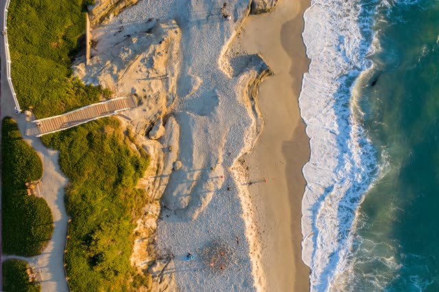Aerial view of the beach, the surf and the ocean at Windansea, with people walking.