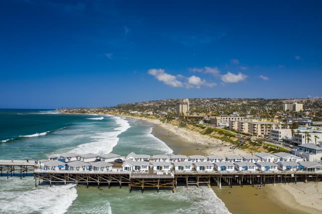 Aerial view of the beach, the surf and the pier in Pacific Beach, with people walking.