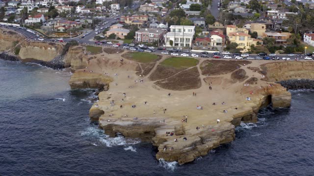 Aerial view of the cliffs, the ocean and homes at Sunset Cliffs, with a crowd gathered.