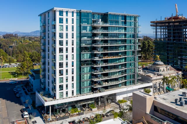Low aerial view of the downtown streets, palm trees and homes at Bankers Hill, with people eating outside.