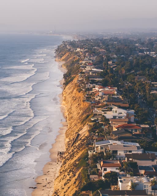 Aerial view of the cliffs, palm trees and the ocean in Encinitas, with people walking.