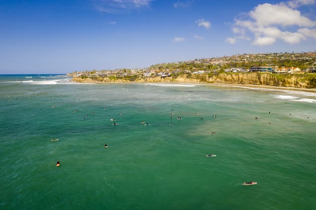 Aerial view of the beach, the surf and the ocean in Pacific Beach, with surfers out.