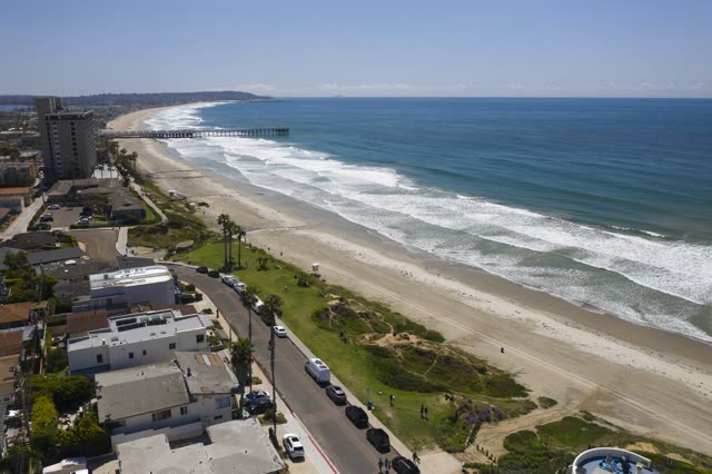 Aerial view of the beach, the surf and the pier in Pacific Beach, with people walking.