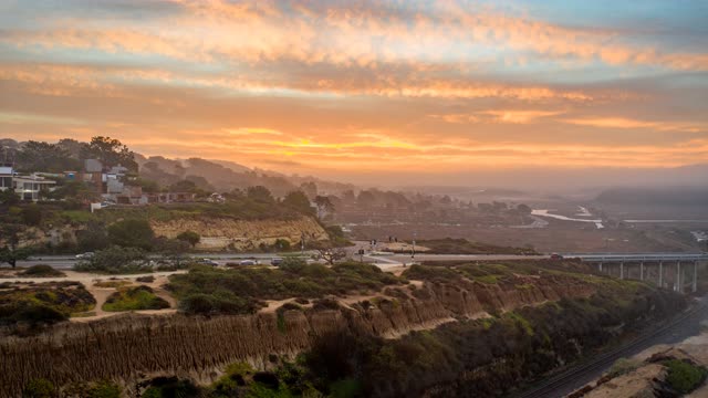 Aerial view of the cliffs, the bridge and homes at Torrey Pines, with people walking.