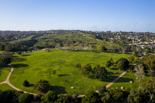 Aerial view of a park, homes and traffic in Pacific Beach, with people walking.