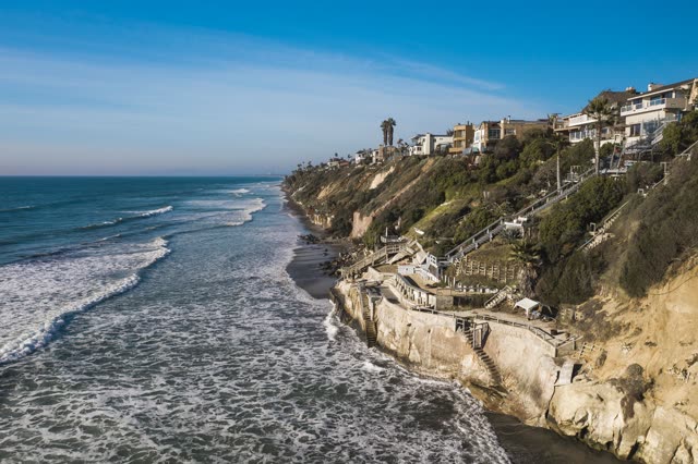 Aerial view of the cliffs, the surf and palm trees in Encinitas.