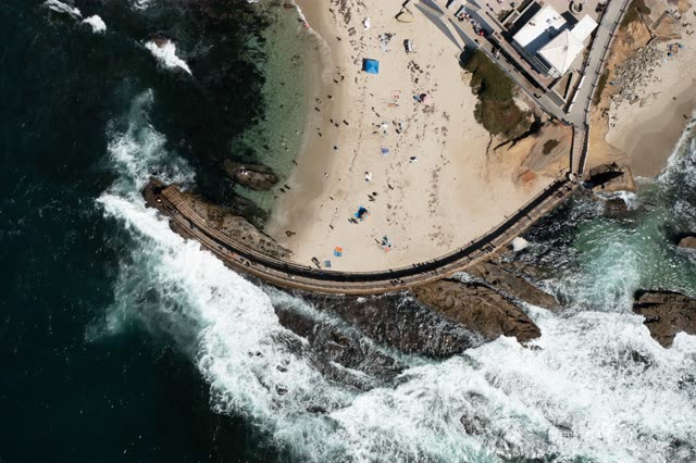 Aerial view of the beach, the surf and the ocean at La Jolla Cove, with a crowd gathered.