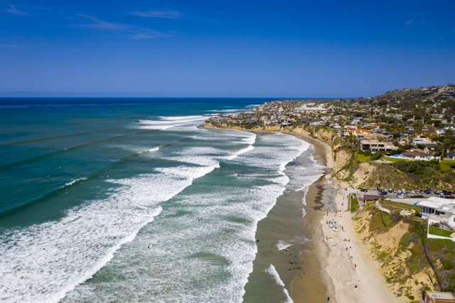 Aerial view of the beach, the surf and the ocean in Pacific Beach, with people walking.