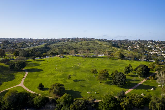Aerial view of a park, homes and traffic in Pacific Beach, with a crowd gathered.