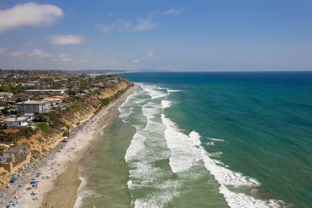 Aerial view of the beach, the surf and the ocean at Moonlight Beach, with people walking.