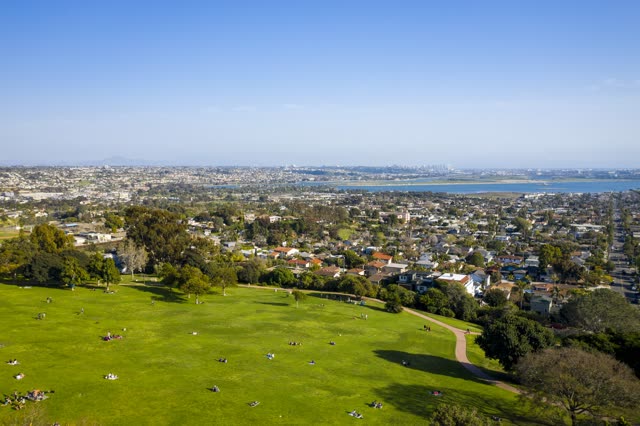 Aerial view of a park, the skyline and the bay in Pacific Beach, with a crowd gathered.