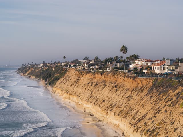 Aerial view of the cliffs, the surf and palm trees in Encinitas.