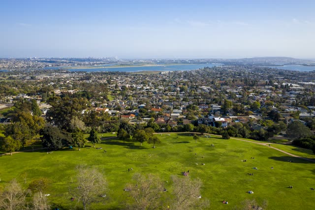 Aerial view of a park, the skyline and the bay in Pacific Beach, with a crowd gathered.