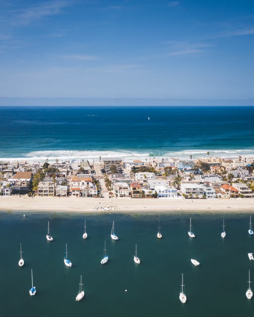 Aerial view of the beach, the surf and boats in Mission Bay, with boats out.