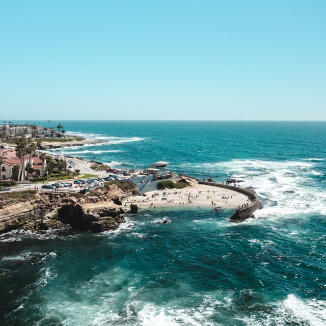 Aerial view of the beach, the surf and the ocean at La Jolla Cove, with a crowd gathered.