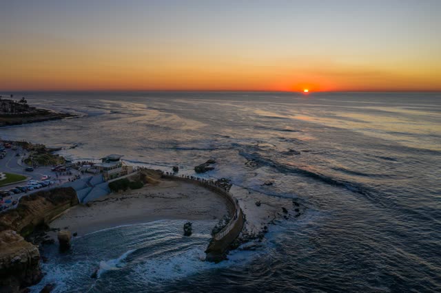 Aerial view of the cliffs, the ocean and the beach at La Jolla Cove, with a crowd gathered.
