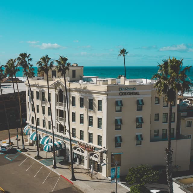 Low aerial view of the downtown streets, palm trees and the ocean at La Jolla Cove.