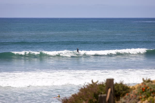 Elevated view of the beach, the surf and the ocean in Pacific Beach, with surfers out.