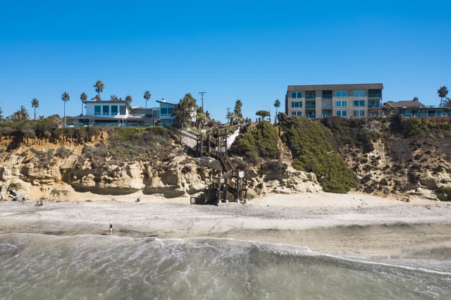 Low aerial view of the beach, the surf and palm trees in Encinitas, with people walking.