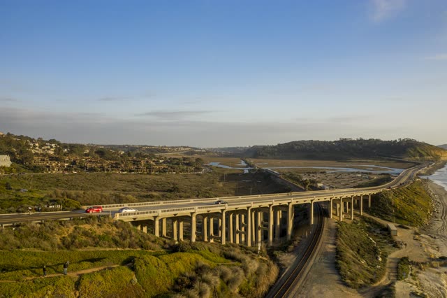 Aerial view of the country inland, the bridge and homes in Del Mar, with people walking.