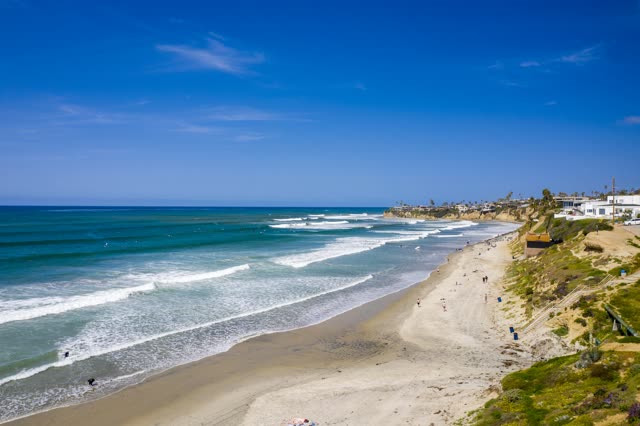 Aerial view of the beach, the surf and the ocean in Pacific Beach, with people walking.