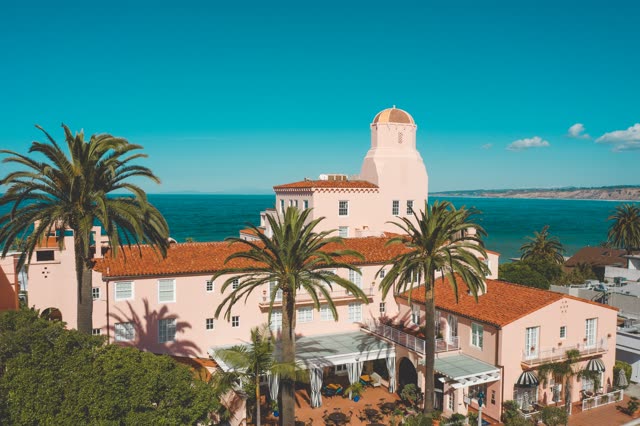 Low aerial view of the beach, palm trees and the ocean at La Jolla Cove.