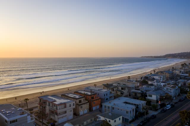 Aerial view of the beach, the surf and palm trees in Mission Bay, with people walking.