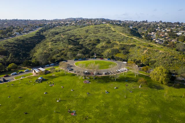 Aerial view of a park, homes and traffic in Pacific Beach, with a crowd gathered.
